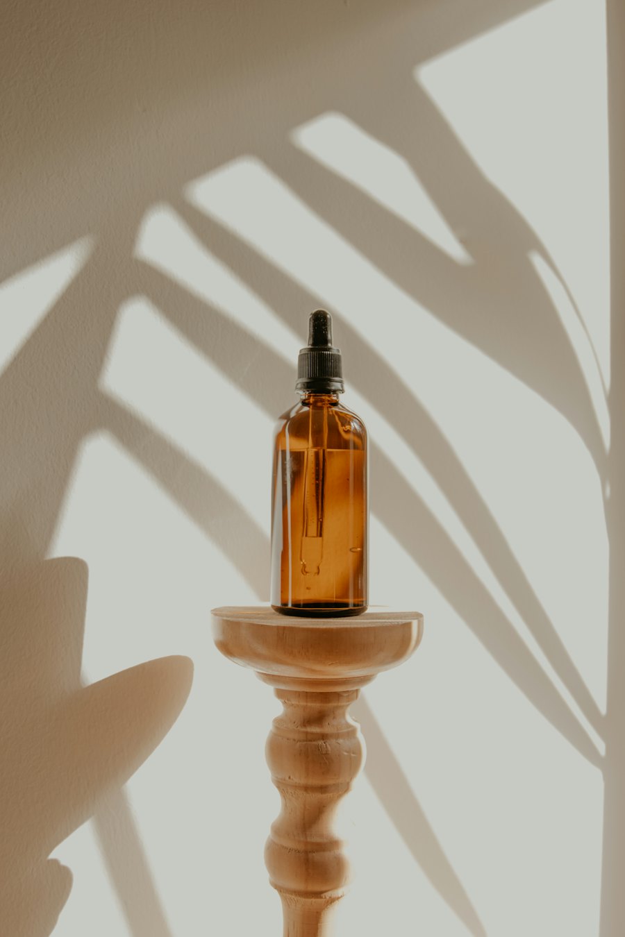 Frasco de producto con luz natural y sombras, encuadre vertical