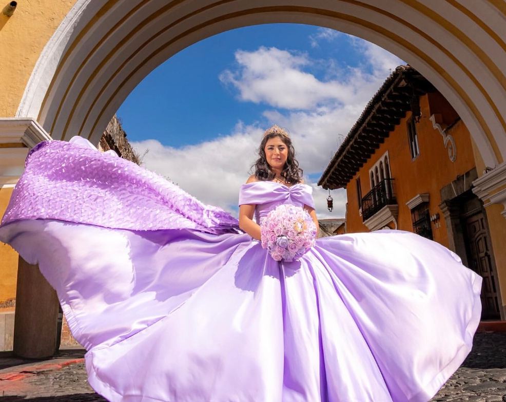 Quinceañera con vestido lila en un arco colonial